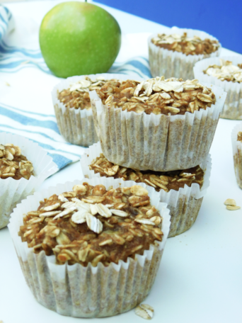 A stack of apple banana oat toddler muffins with a green apple in the background.