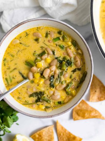 Asparagus White Bean Soup in a bowl with chips next to it.