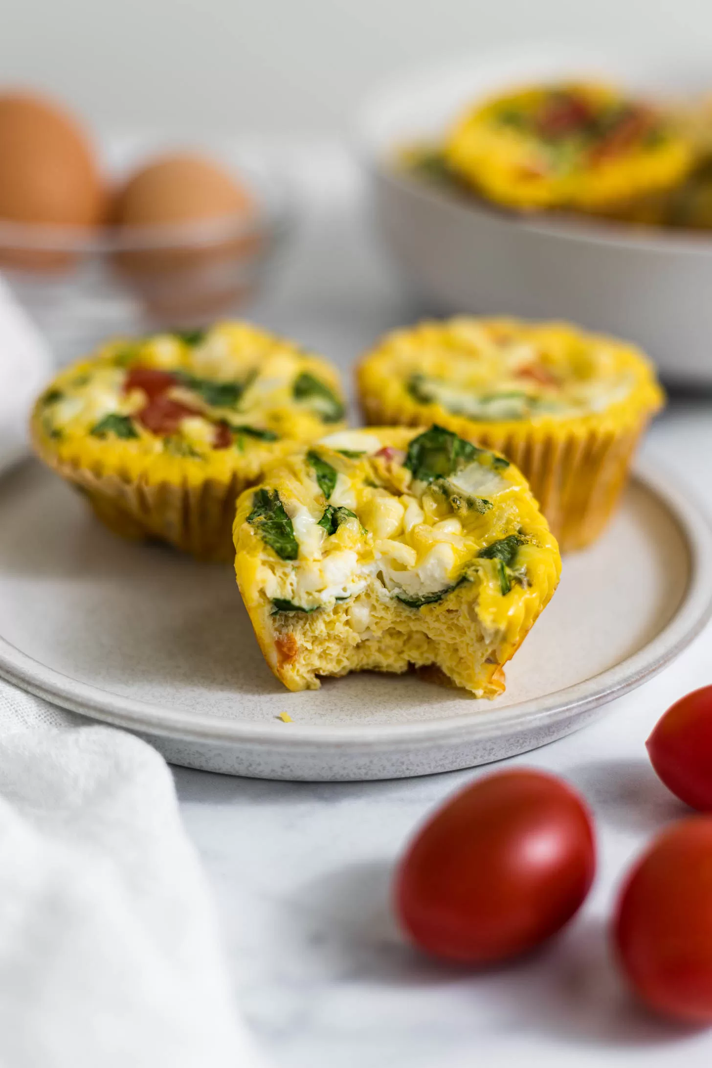 Plate of egg muffins, one with a bite out of it.