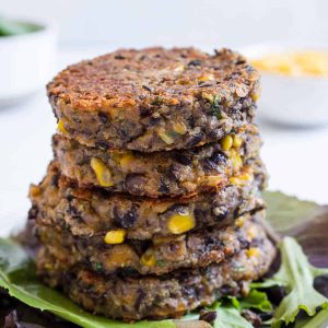 A stack of black bean fritters on a bed of lettuce.