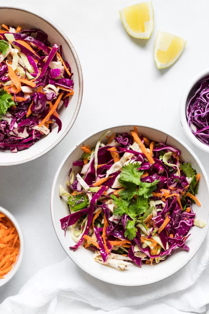 An overhead view of two bowls of coleslaw. 