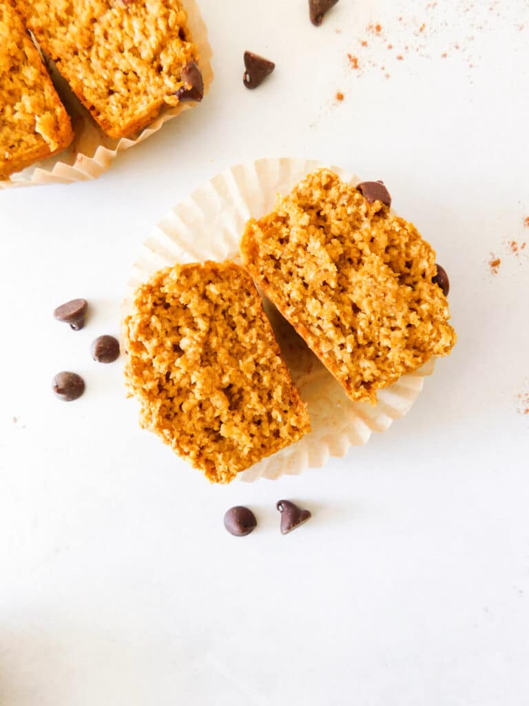 A pumpkin oat flour muffin is cut in half.