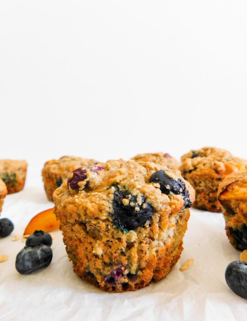 A blueberry nectarine muffin with more muffins behind it.