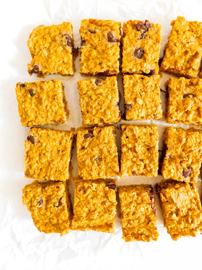 An overhead view of healthy pumpkin bars that are sitting in rows. Several of the bars are slightly angled and are spread out from each other.