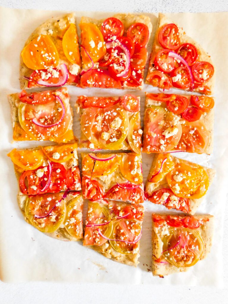 A hummus pizza that is cut into square slices.