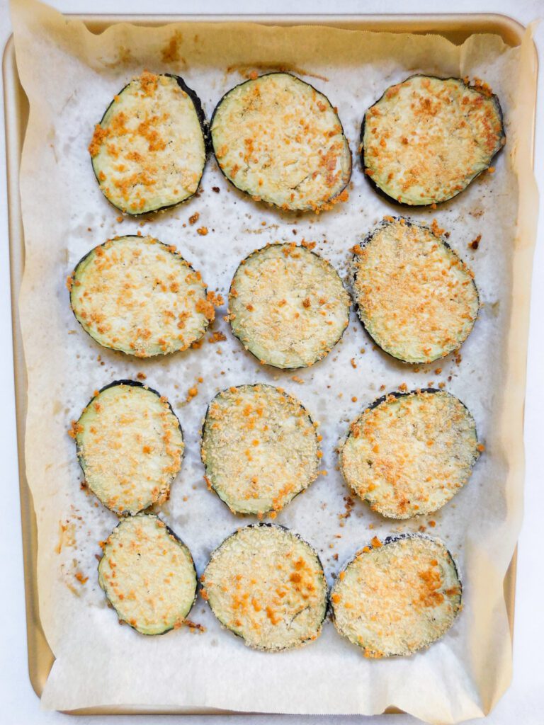 Eggplant rounds on a baking sheet before the toppings are added.
