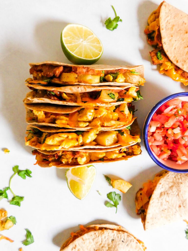 An overhead view of Vegetarian Breakfast Tacos pushed together by two lime wedges.