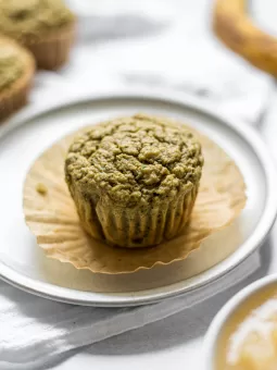 A Spinach Banana Muffin sitting on a small plate. The plate sits on top of a linen cloth.
