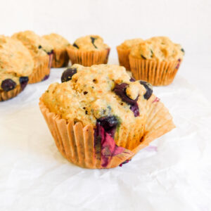 A Vegan Blueberry Muffin with some sitting behind it.