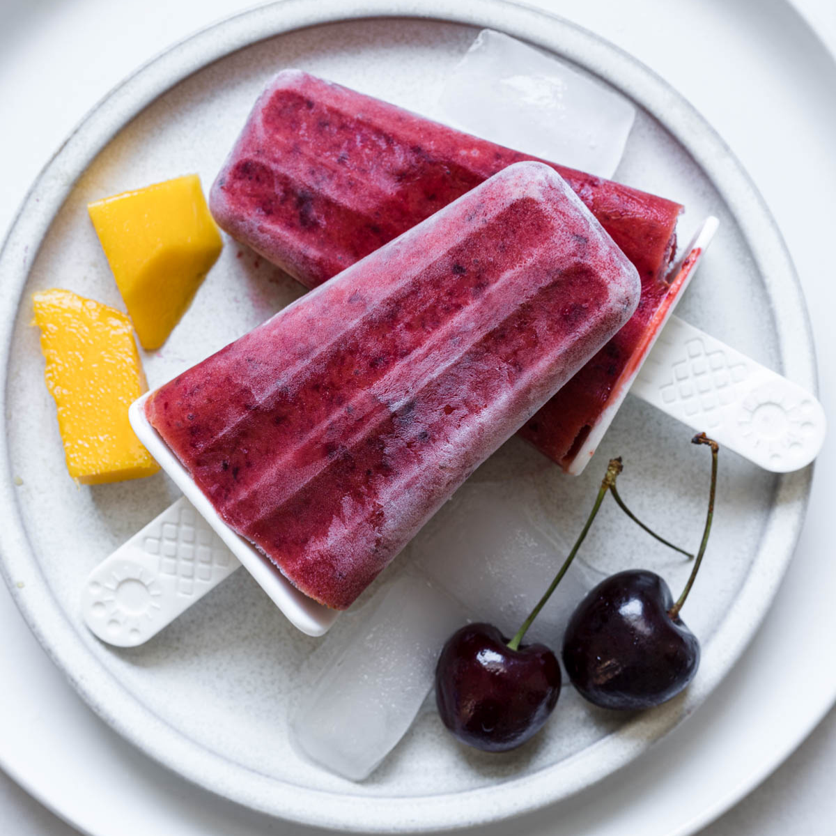 Cherry mango popsicles on a plate.