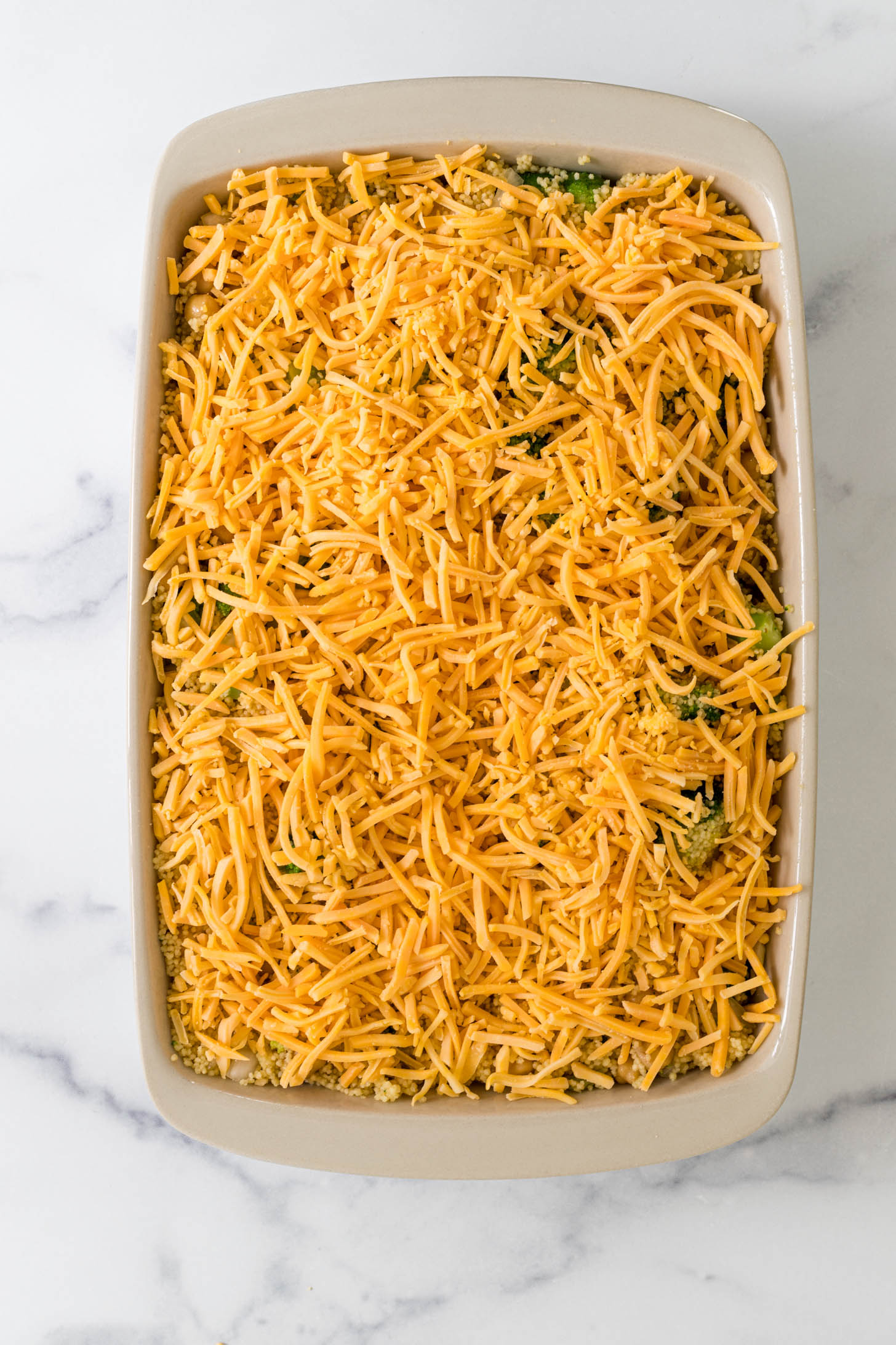 Shredded cheese layered over ingredients in a baking dish.