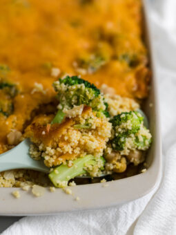 A spoon scooping out the couscous casserole with a piece of broccoli in it.