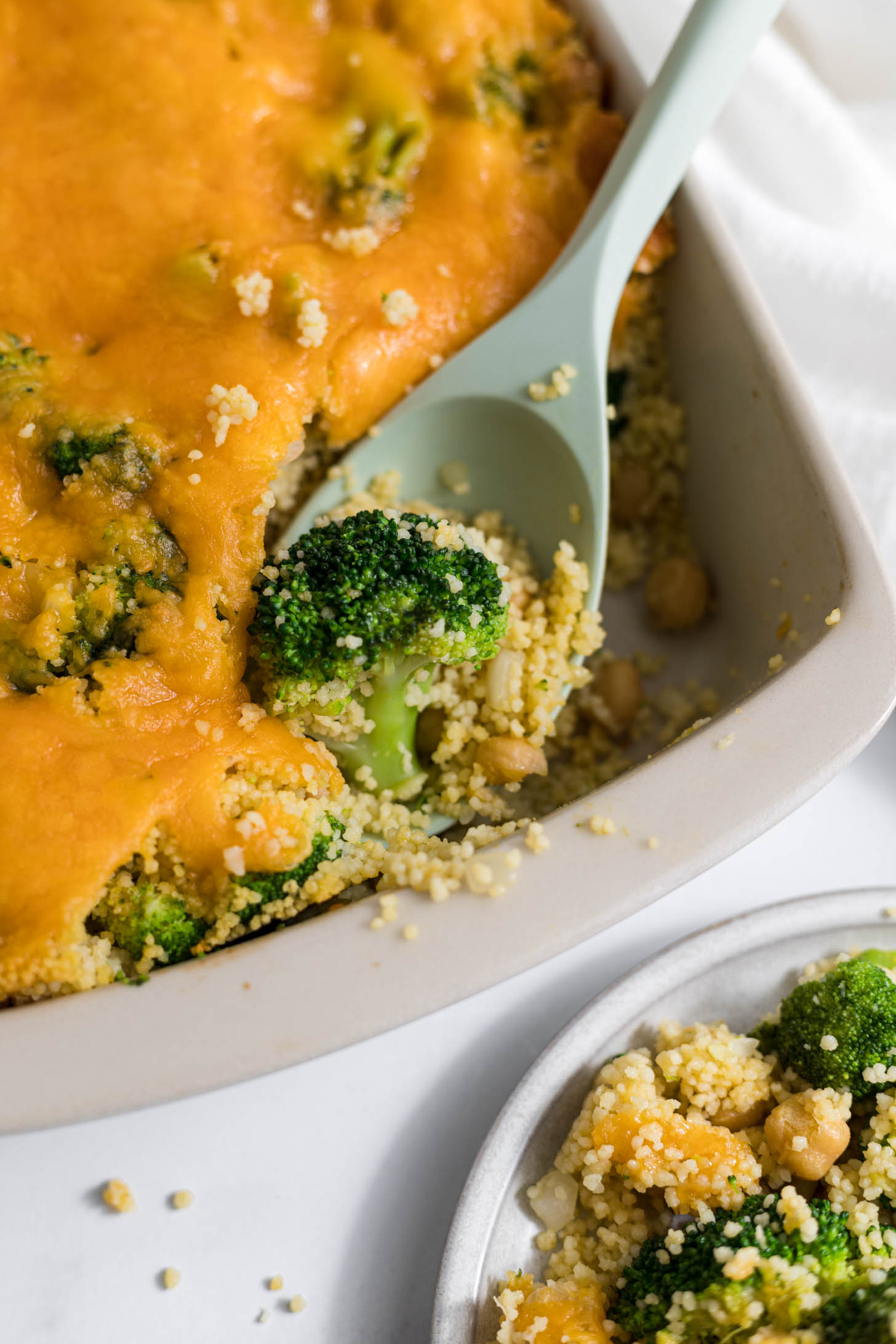 A serving spoon scooping out couscous and broccoli.