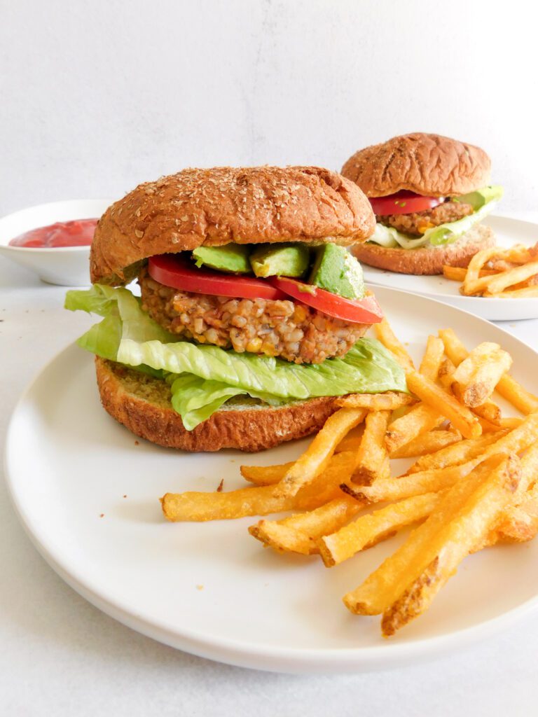Two veggie burgers on two plates served with french fries.