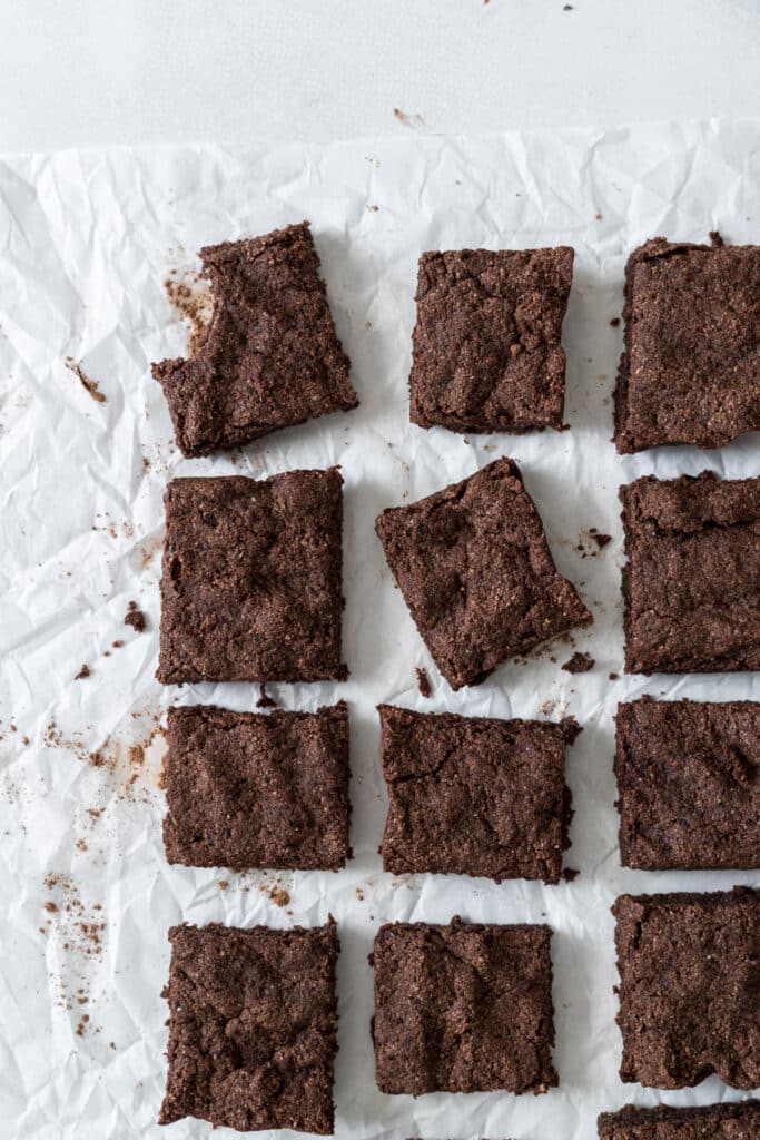 Brownies sit in rows. One has a bite out of it and another one is slightly turned.