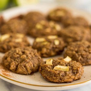 A plate of apple peanut butter cookies with green apples in the background.