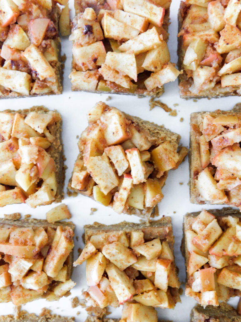 A close up view of apple pie bars in rows, one is sitting slightly sideways.
