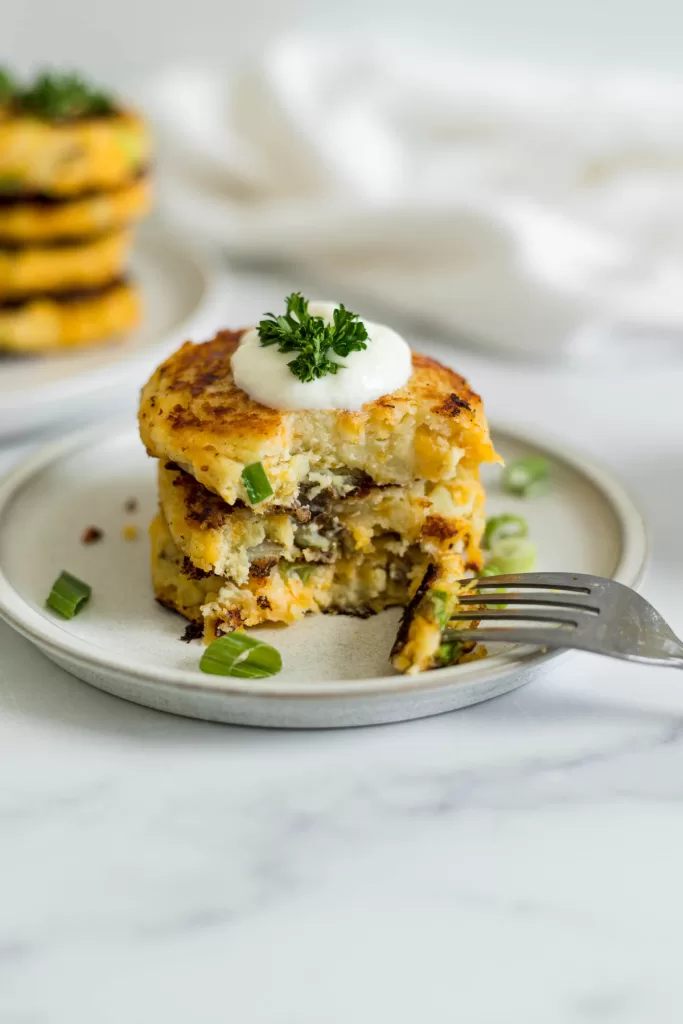 An angled view of a stack of three potato pancakes with a bite out them.