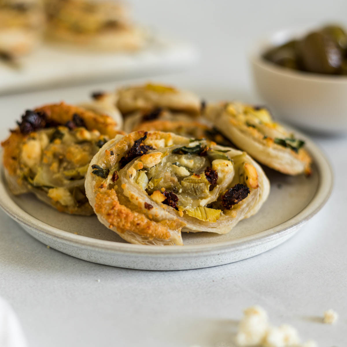 Mediterranean puff pastry pinwheels on a plate.