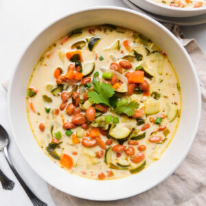 A bowl of Quick Vegan Pinto Bean Soup. Another bowl of soup sits off to the side and some spoons.