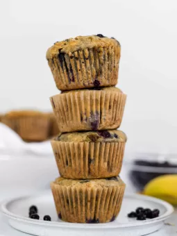 A stack of 4 Banana Blueberry Oatmeal Muffins on a plate.