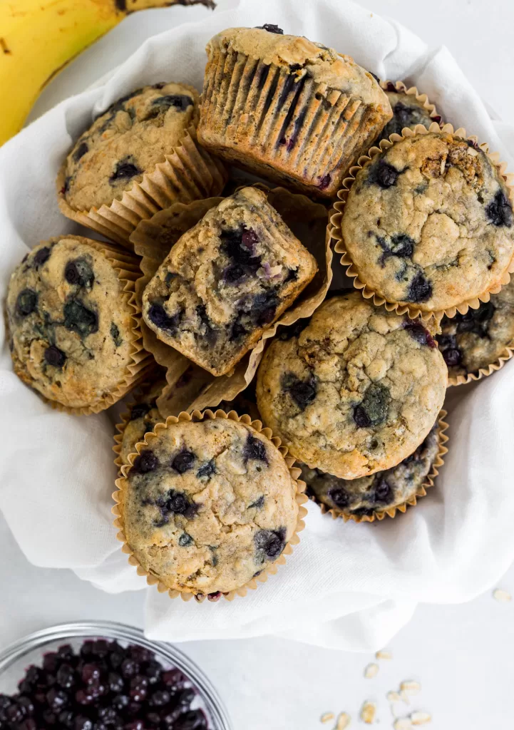 Overhead view of blueberry muffins in a bowl with one cut in half.