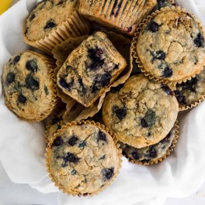Overhead view of blueberry muffins in a bowl with one cut in half.