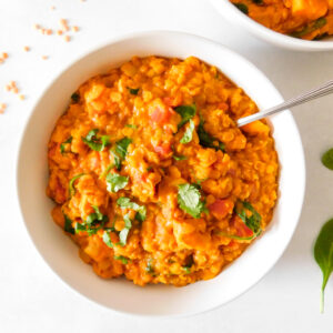 A bowl of Red Lentil Curry With Sweet Potato and Spinach.