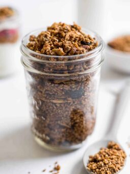 A jar of steel-cut oat granola with a spoonful of granola next to it.