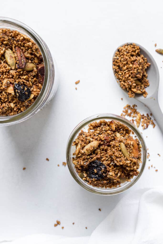An overhead view of two jars of granola and spoonful of granola.