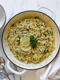A pan of Orzo With Spinach and Feta. Two lemon slices and parsley decorate the middle of the pan.