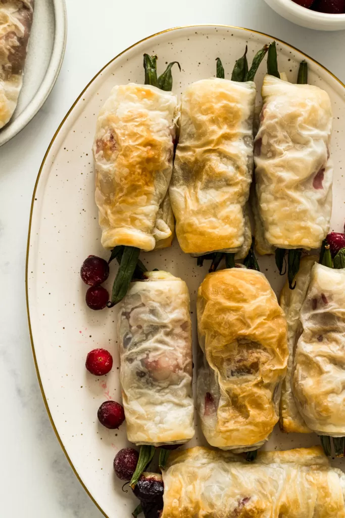 Overhead view of green bean bundles with puff pastry on a plate.