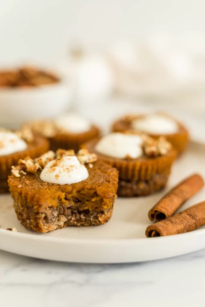 A pumpkin tart with a bite out of it on a plate with other tarts.