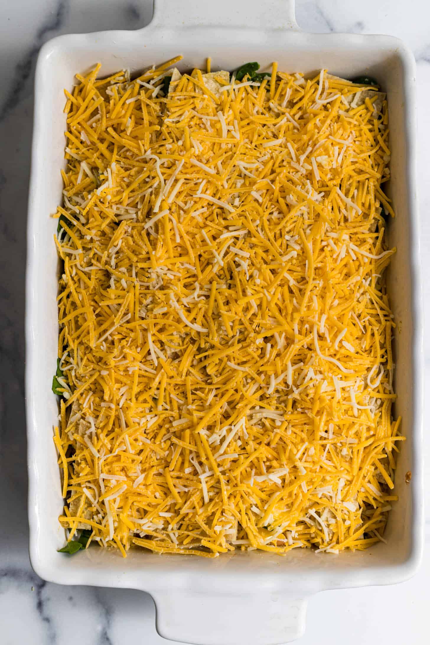 Assembled taco casserole in a baking dish that's ready to go in the oven.