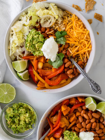 Two Vegetarian Fajita Bowls with a small bowl of guacamole on the side.