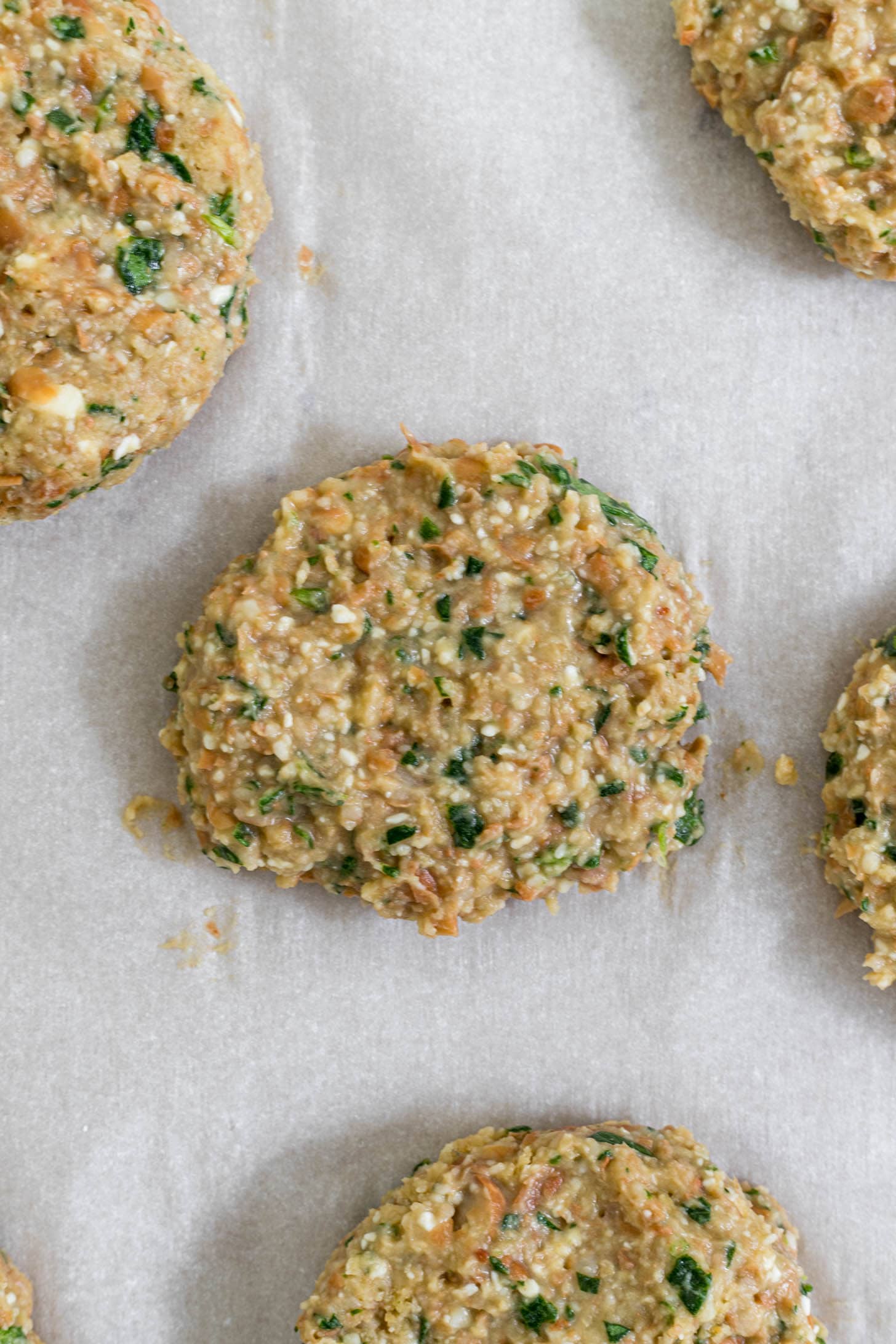 Burger patties uncooked on a baking sheet.