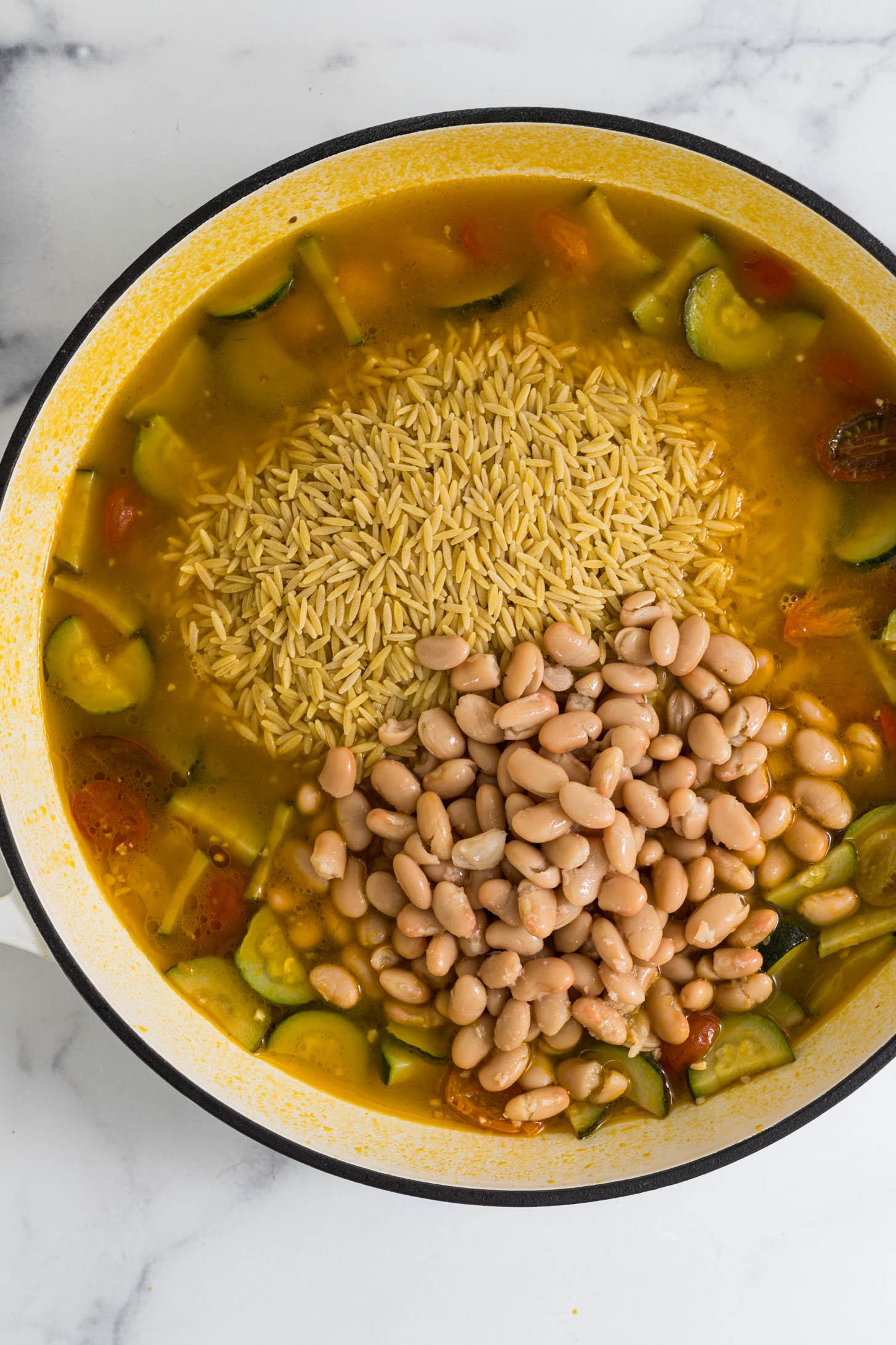 White beans and orzo is added to the pot.