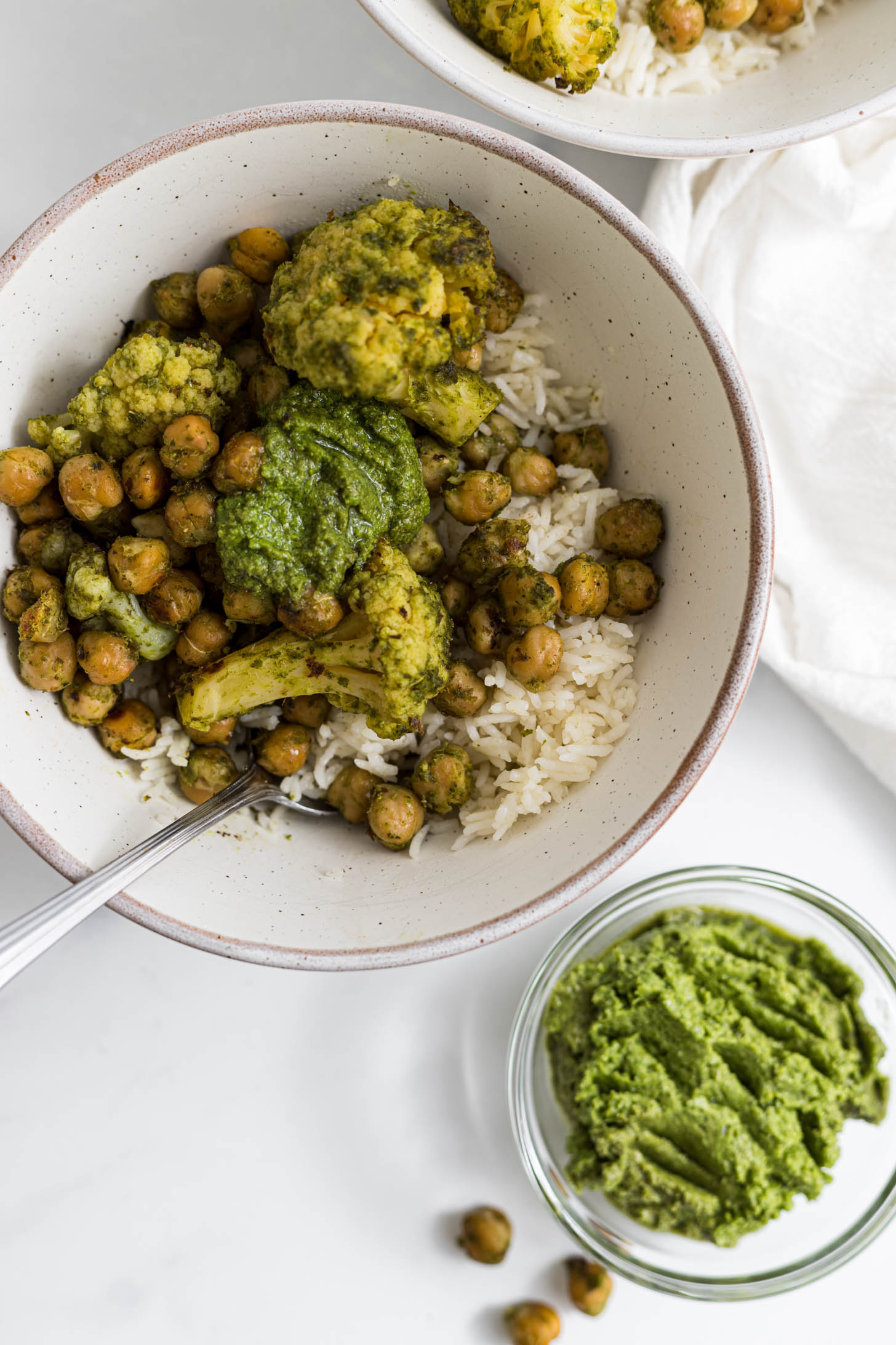 Overhead view of pesto chickpeas in a bowl with a side of pesto.