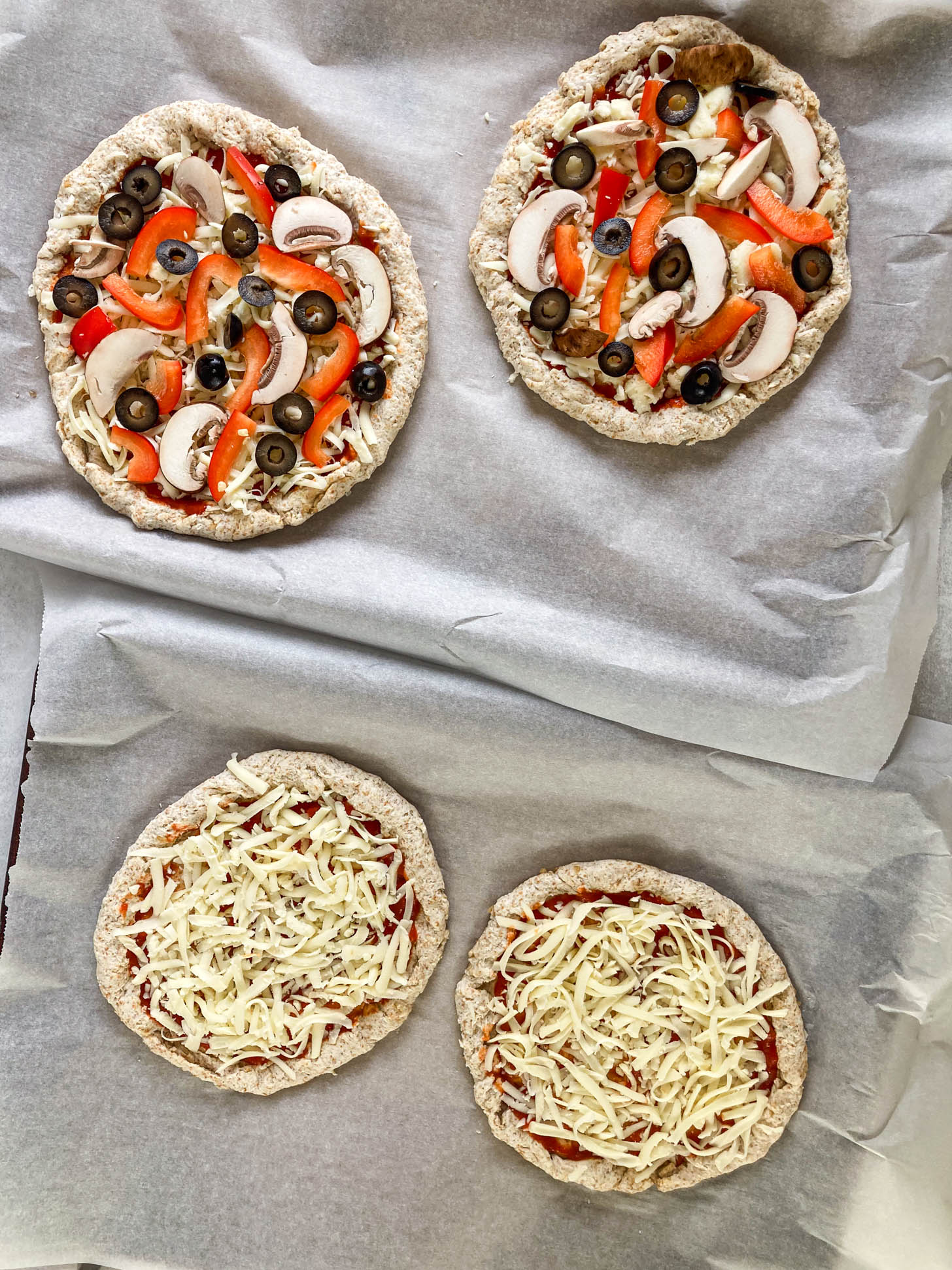 Protein pizza with toppings on them ready to go in the oven.