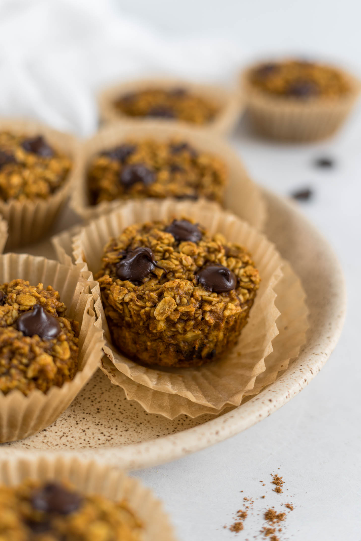 A muffin in a muffin liner on a plate.