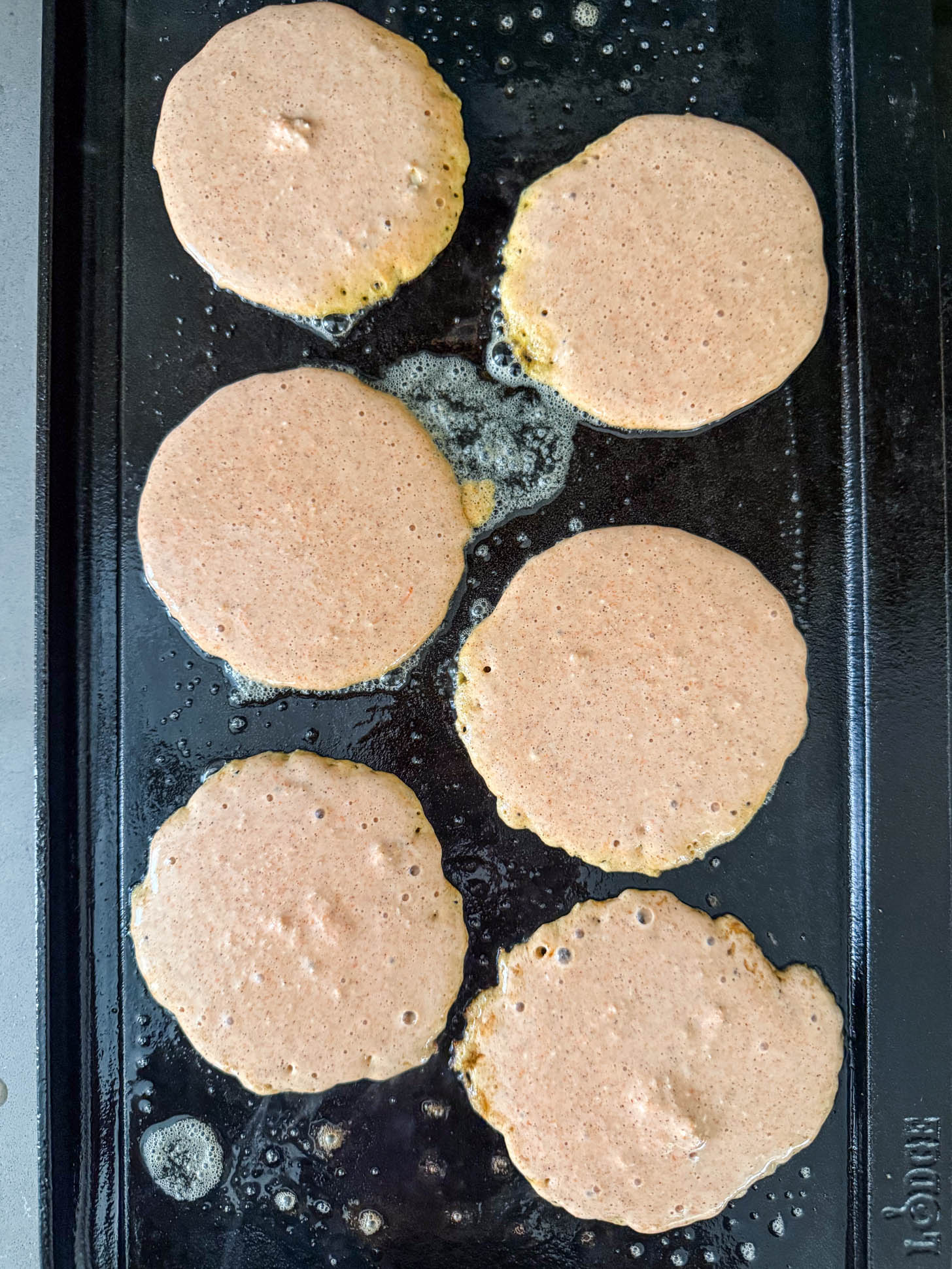 Pancakes cooking on a griddle.