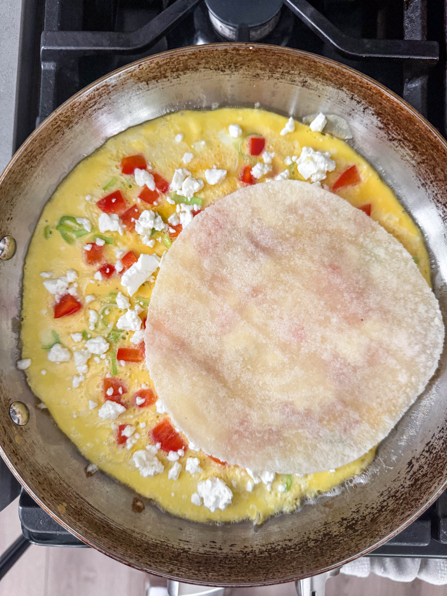 Omelette ingredients in a pan with an almond flour tortilla.