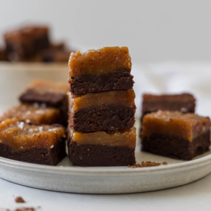 Peanut butter chocolate fudge squares stacked on a plate.