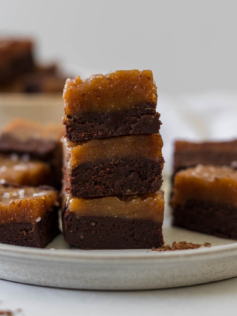 Peanut butter chocolate fudge squares stacked on a plate.