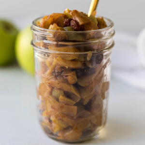 A jar of apple compote with a spoon in it.