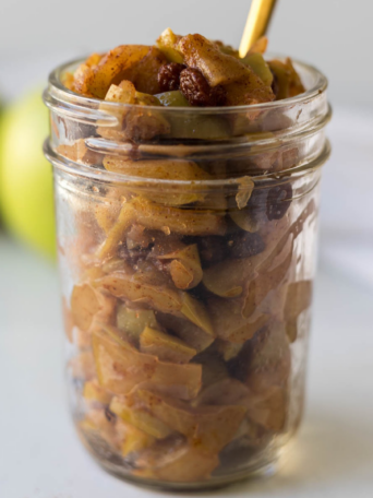 A jar of apple compote with a spoon in it.