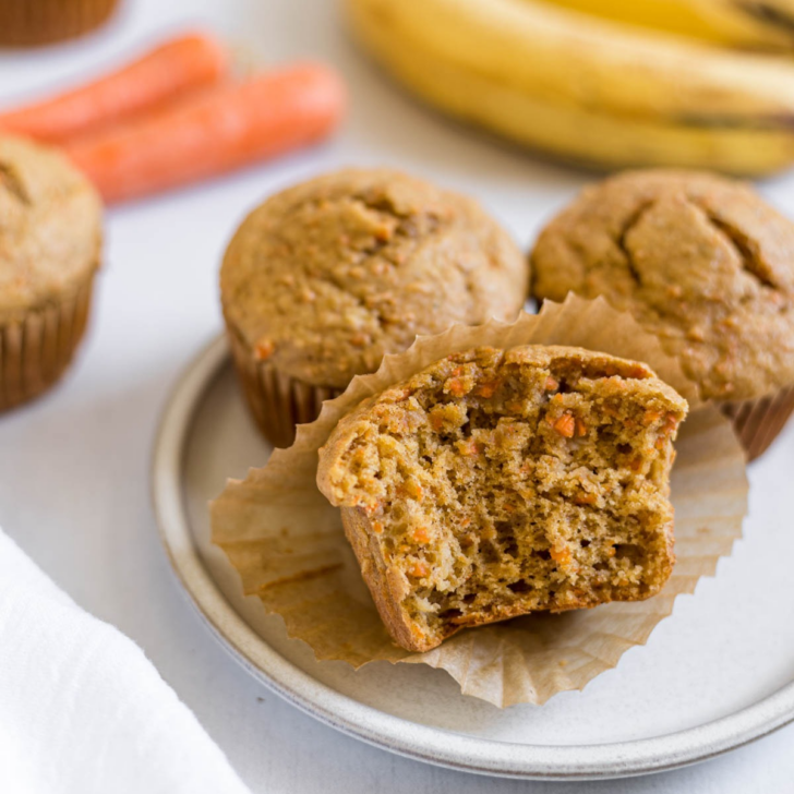 A banana carrot muffin with a bite out of it on a plate.